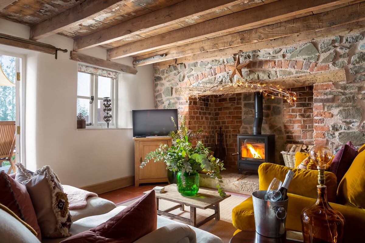 Sitting room with wood burning stove, sofas, table and exposed wooden beams