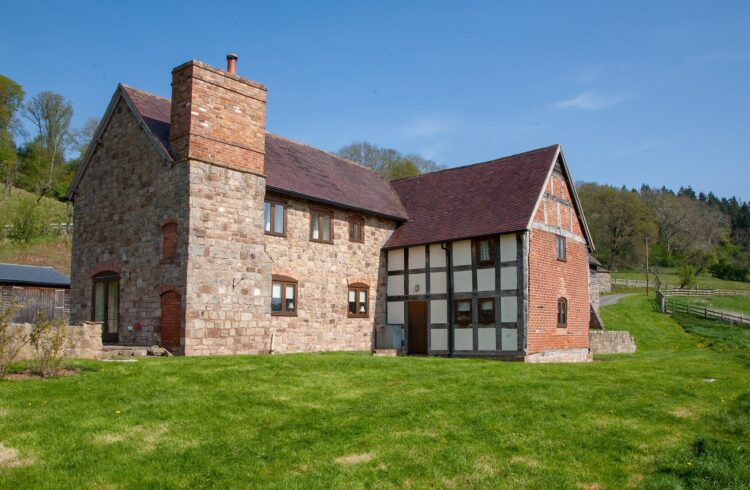 Exterior view of part-timber-framed cottage with grass around