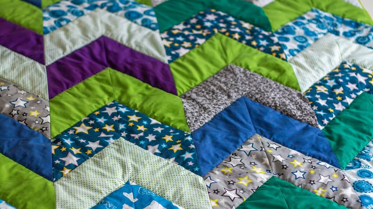 A quilt in a chevron design including stars, purple, blue and green