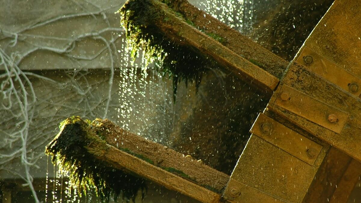 A water mill captured in movement, with droplets of water falling